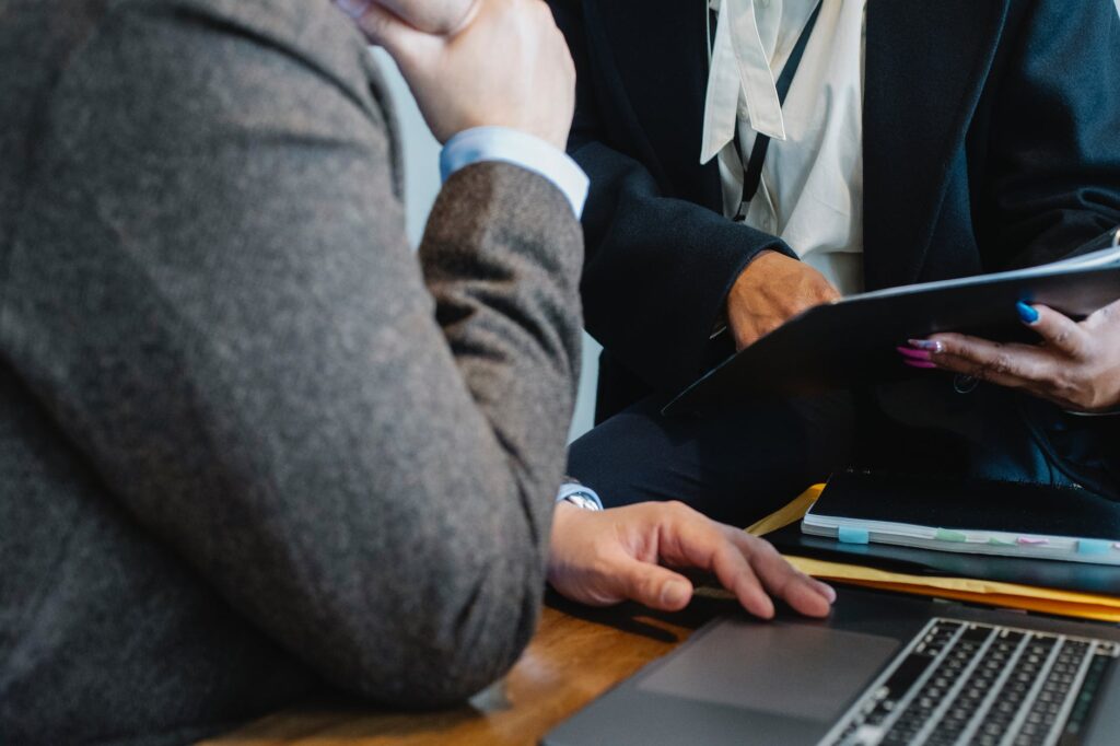 crop female employee pointing at document while working in office with male colleague