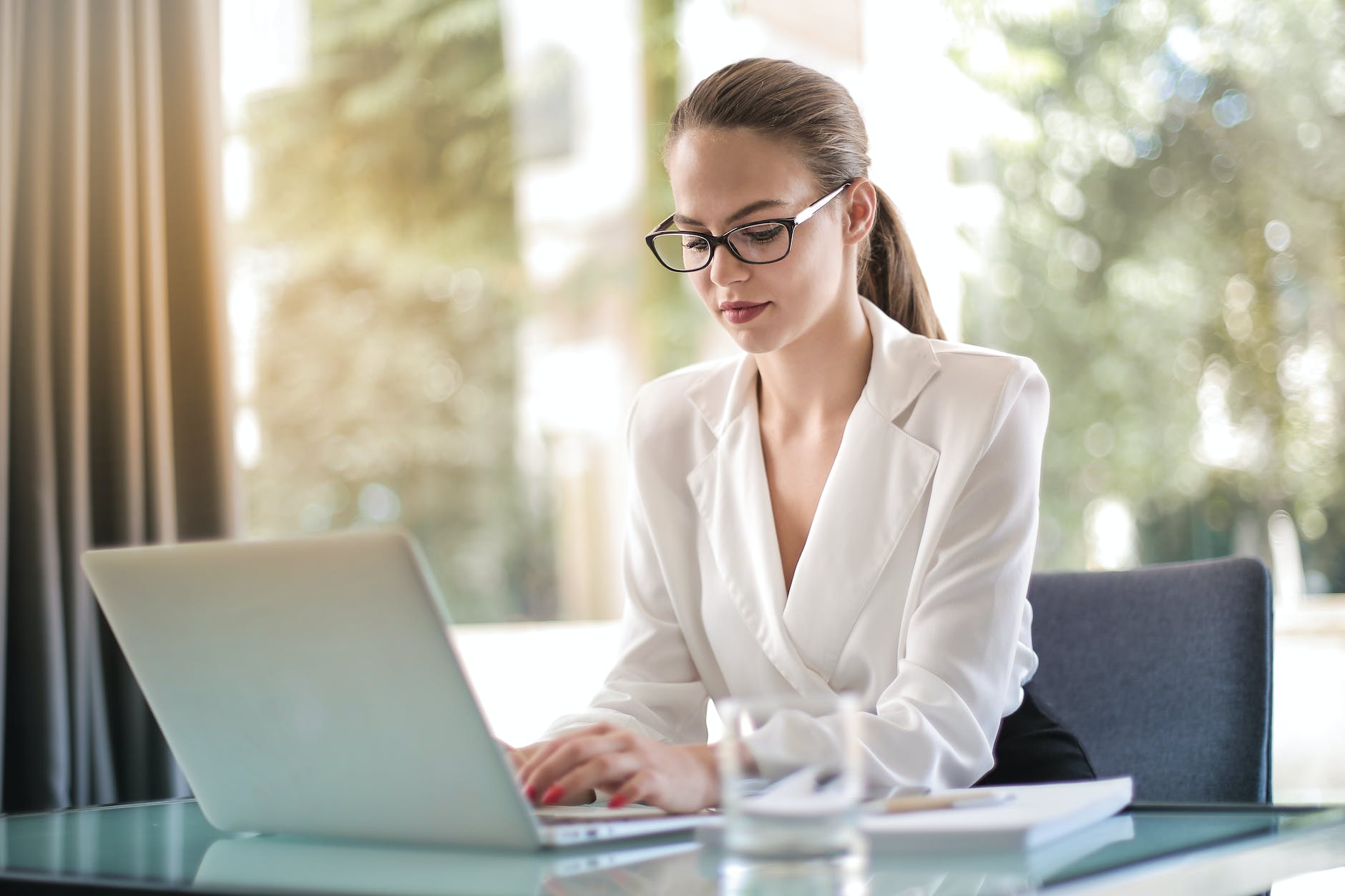 concentrated female entrepreneur typing on laptop in workplace